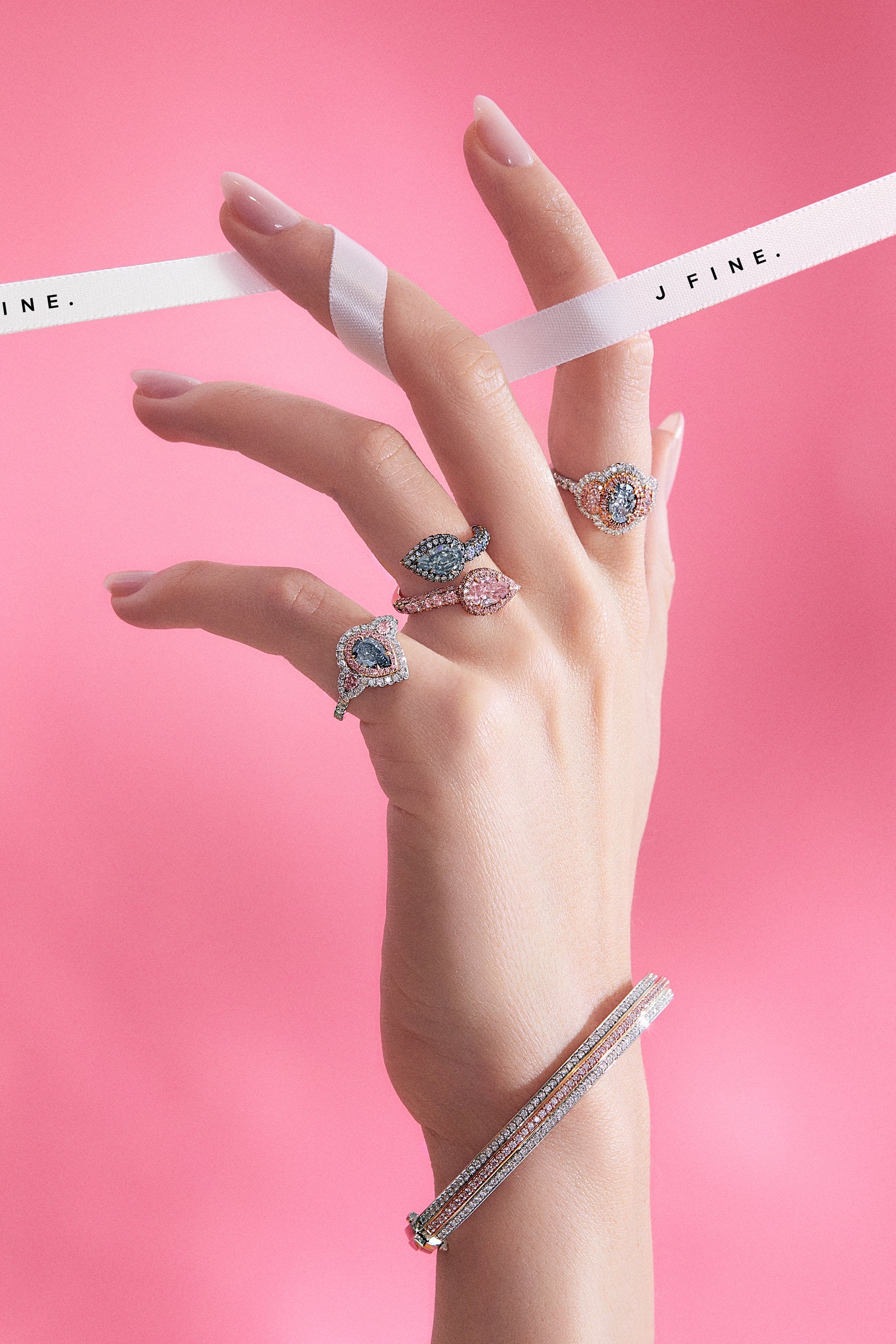 Fashion model wearing JFINE's pear shape blue diamond ring and oval blue diamond ring